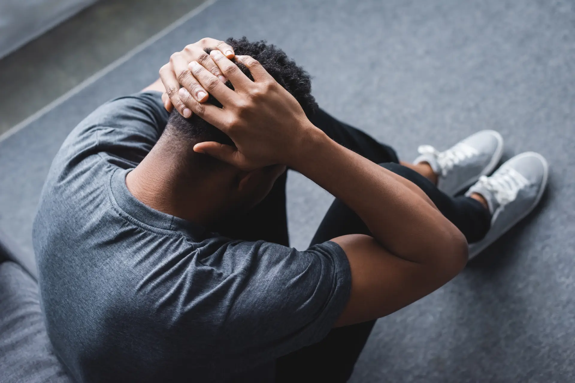 Man sitting on couch with head in hands